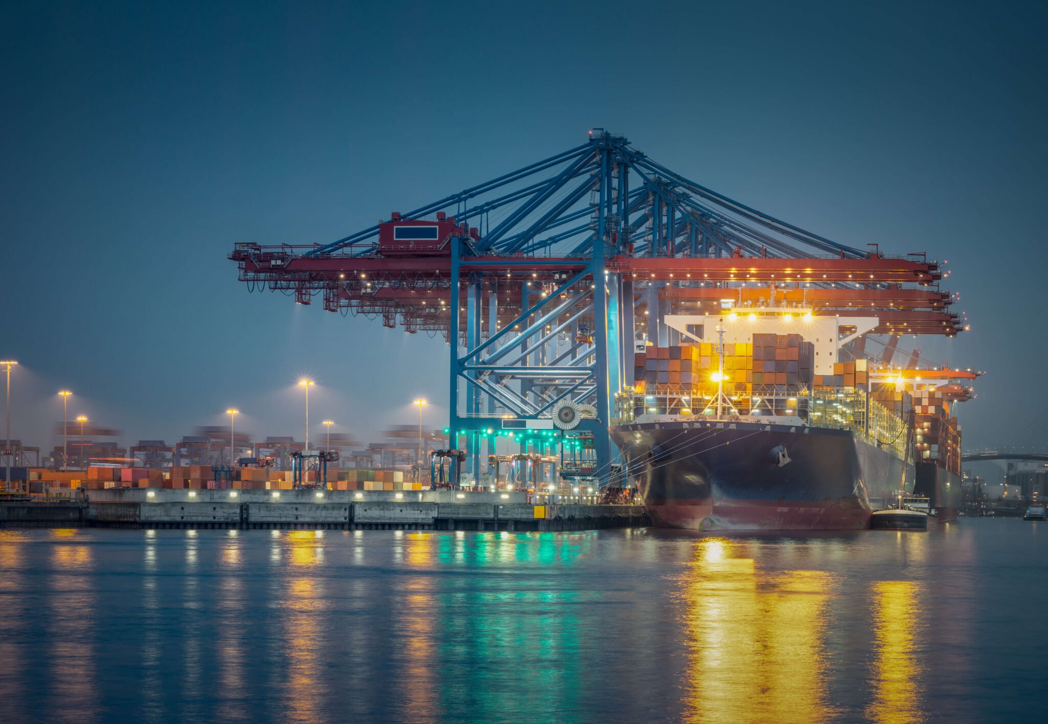 Containerterminal bei Nacht mit beleuchteten Verladebrücken